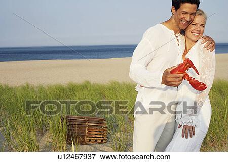 Close-up of a mature man holding a lobster and embracing a mature woman on the beach View Large Photo Image Stock Photo - Close-up of a mature man holding a lobster and embracing a mature woman on the beach. Fotosearch