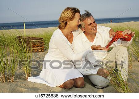 Close-up of a mature man holding a lobster with a mature woman kneeling beside him on the beach View Large Photo Image Stock Photograph - Close-up of a mature man holding a lobster with a mature woman kneeling beside him on the beach. Fotosearch