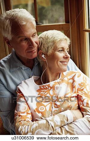 Close-up of a senior woman wearing headphones and smiling with a mature man View Large Photo Image Stock Photo - Close-up of a senior woman wearing headphones and smiling with a mature man. Fotosearch