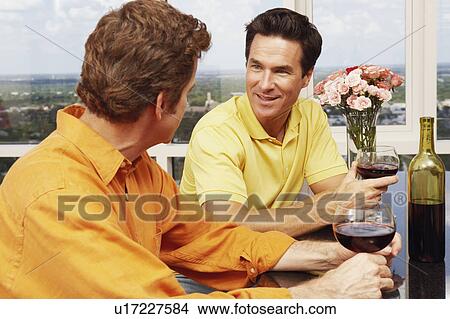 Close-up of two mature men holding glasses of wine and talking View Large Photo Image Picture - Close-up of two mature men holding glasses of wine and talking. Fotosearch