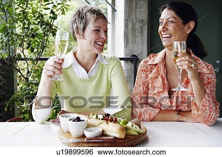 Close-up of two mature women holding champagne flutes and smiling View Large Photo Image Stock Photograph - Close-up of two mature women holding champagne flutes and smiling. Fotosearch