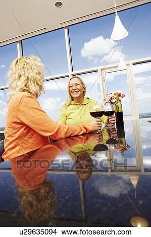 Low angle view of a mature woman and a mid adult woman holding glasses of wine View Large Photo Image Picture - Low angle view of a mature woman and a mid adult woman holding glasses of wine. Fotosearch