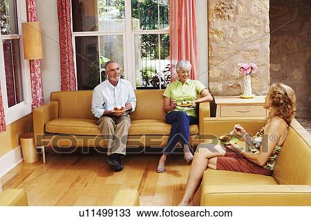 Stock Image - Mature couple and a senior woman sitting on a couch. Fotosearch
