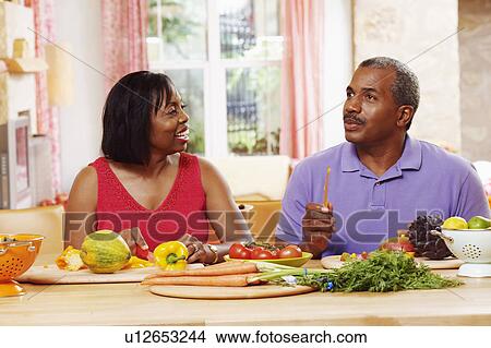 Mature couple cutting vegetables and talking View Large Photo Image Picture - Mature couple cutting vegetables and talking. Fotosearch