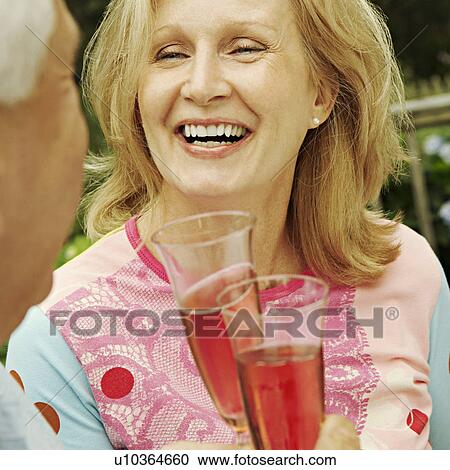 Mature couple holding champagne flutes and smiling View Large Photo Image Stock Image - Mature couple holding champagne flutes and smiling. Fotosearch