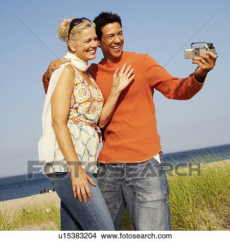 Mature couple taking a picture of themselves on the beach View Large Photo Image Picture - Mature couple taking a picture of themselves on the beach. Fotosearch
