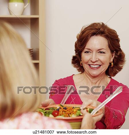 Mature woman giving a bowl of salad to her friend and smiling View Large Photo Image Stock Photo - Mature woman giving a bowl of salad to her friend and smiling. Fotosearch