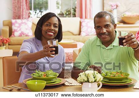 Stock Photo - Portrait of a mature couple holding glasses of drink and smiling. Fotosearch