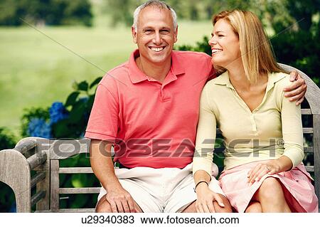 Stock Image - Portrait of a mature man sitting with his arm around a mid adult woman and smiling. Fotosearch