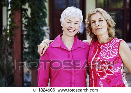 Stock Photograph - Portrait of a mature woman and a senior woman standing together and smiling. Fotosearch