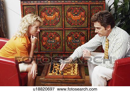 Stock Photo - Side profile of a businessman and a businesswoman playing chess. Fotosearch