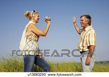 Side profile of a mature woman taking a picture of a mature man with a digital camera View Large Photo Image Stock Image - Side profile of a mature woman taking a picture of a mature man with a digital camera. Fotosearch