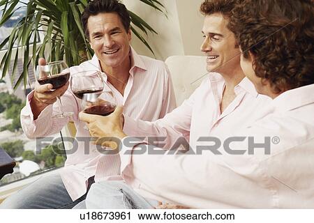 Stock Image - Three mature men toasting a drink. Fotosearch