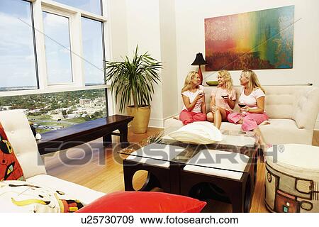 Three women sitting together and holding glasses of wine View Large Photo Image Stock Photo - Three women sitting together and holding glasses of wine. Fotosearch