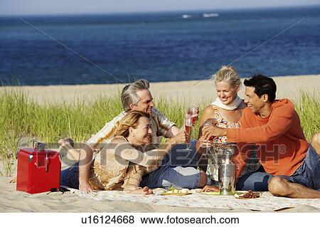 Two mature couples sitting on the beach and toasting with champagne View Large Photo Image Stock Photo - Two mature couples sitting on the beach and toasting with champagne. Fotosearch