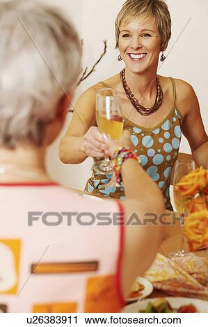 Stock Image - Two women toasting with champagne flutes. Fotosearch
