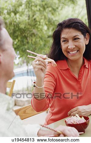 Close-up of a mature woman feeding a mature man with chopsticks View Large Photo Image Stock Image - Close-up of a mature woman feeding a mature man with chopsticks. Fotosearch