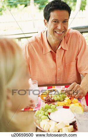 Stock Image - Mature man sitting at a table with a woman in front of him. Fotosearch