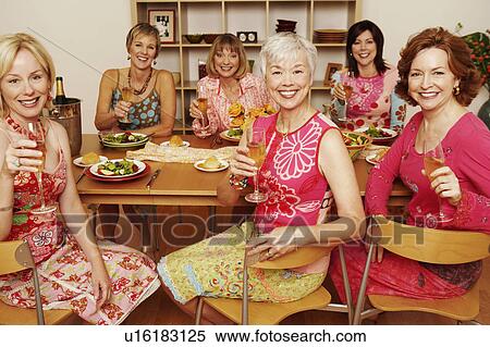 Portrait of a group of mature women sitting at the dining table and holding champagne flutes View Large Photo Image Stock Photography - Portrait of a group of mature women sitting at the dining table and holding champagne flutes. Fotosearch