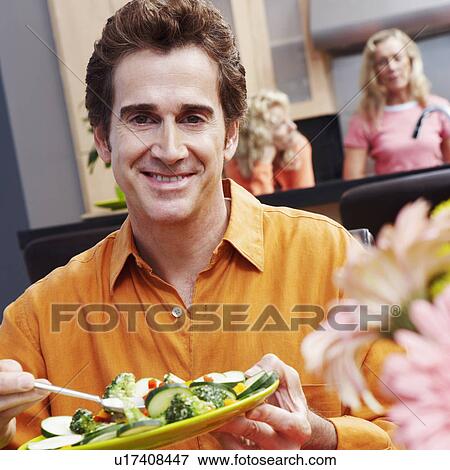 Stock Photo - Portrait of a mature man holding a plate of salad and smiling. Fotosearch
