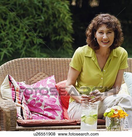 Portrait of a mature woman sitting on a couch and smiling View Large Photo Image Stock Photo - Portrait of a mature woman sitting on a couch and smiling. Fotosearch