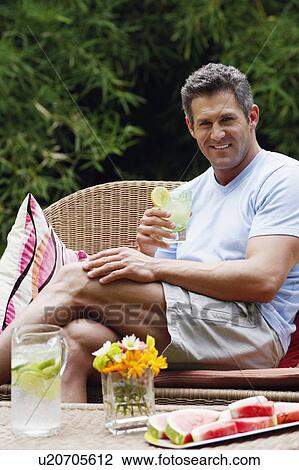 Portrait of a mid adult man holding a glass of lemonade and smiling View Large Photo Image Stock Image - Portrait of a mid adult man holding a glass of lemonade and smiling. Fotosearch