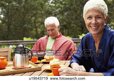 Portrait of a senior woman smiling with a mature man in the background View Large Photo Image Stock Photo - Portrait of a senior woman smiling with a mature man in the background. Fotosearch
