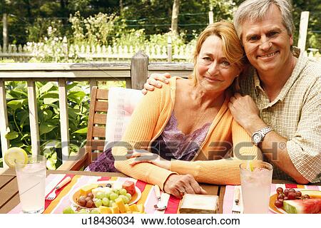 Portrait of a mature couple sitting at the table View Large Photo Image Picture - Portrait of a mature couple sitting at the table. Fotosearch