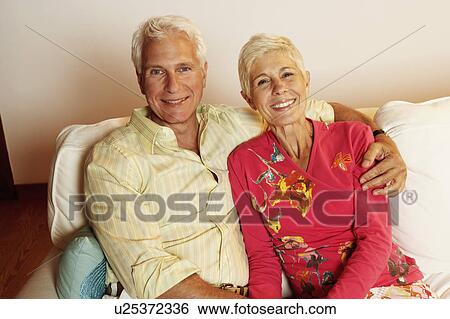 Portrait of a mature man and a senior woman sitting on a couch and smiling View Large Photo Image Stock Photograph - Portrait of a mature man and a senior woman sitting on a couch and smiling. Fotosearch