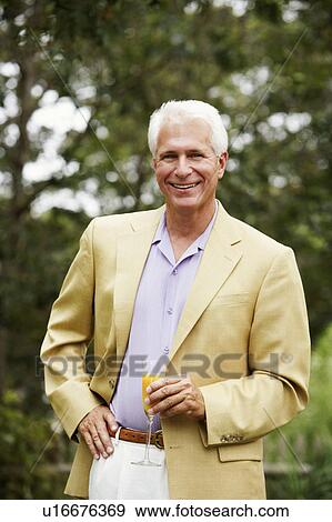 Stock Photo - Portrait of a mature man holding a glass of juice. Fotosearch