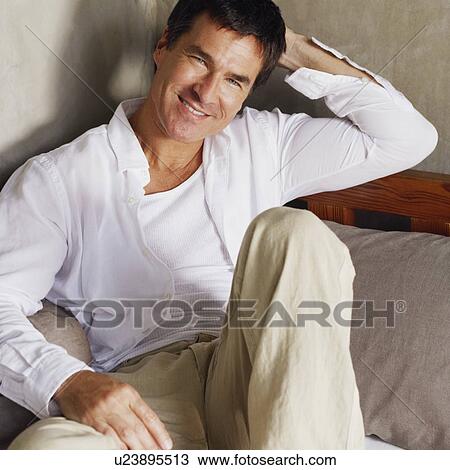 Stock Image - Portrait of a mature man reclining on the bed. Fotosearch