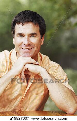 Stock Photo - Portrait of a mature man with his hand on his chin. Fotosearch