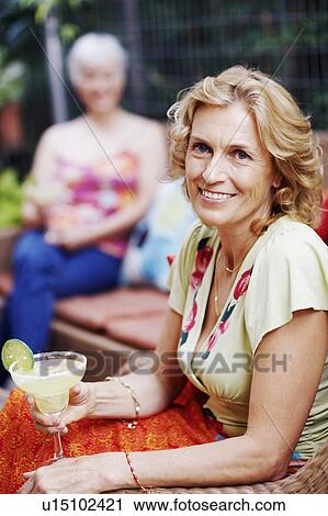 Portrait of a mature woman holding a glass of lemonade and smiling View Large Photo Image Stock Image - Portrait of a mature woman holding a glass of lemonade and smiling. Fotosearch