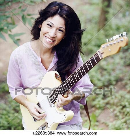 Picture - Portrait of a mature woman playing the guitar. Fotosearch