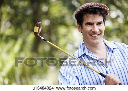 Close-up of a mature man holding a golf club and smiling View Large Photo Image Picture - Close-up of a mature man holding a golf club and smiling. Fotosearch