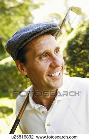Stock Image - Close-up of a mature man holding a golf club and smiling. Fotosearch