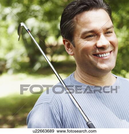 Close-up of a mature man holding a golf club and smiling View Large Photo Image Stock Photo - Close-up of a mature man holding a golf club and smiling. Fotosearch