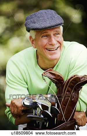 Picture - Close-up of a mature man leaning on a golf bag and laughing. Fotosearch
