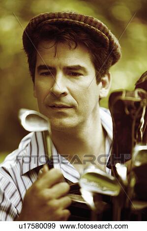 Stock Photo - Close-up of a mature man looking at a golf club. Fotosearch
