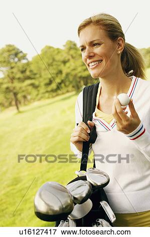 Close-up of a mid adult woman holding a golf ball and a golf bag View Large Photo Image Stock Photo - Close-up of a mid adult woman holding a golf ball and a golf bag. Fotosearch