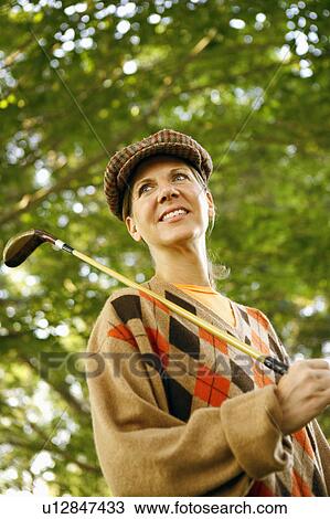 Stock Image - Low angle view of a mature woman holding a golf club. Fotosearch