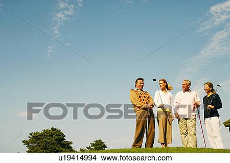 Low angle view of two men and two women holding golf clubs View Large Photo Image Picture - Low angle view of two men and two women holding golf clubs. Fotosearch