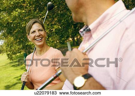 Stock Image - Mature woman and a mature man holding golf clubs. Fotosearch