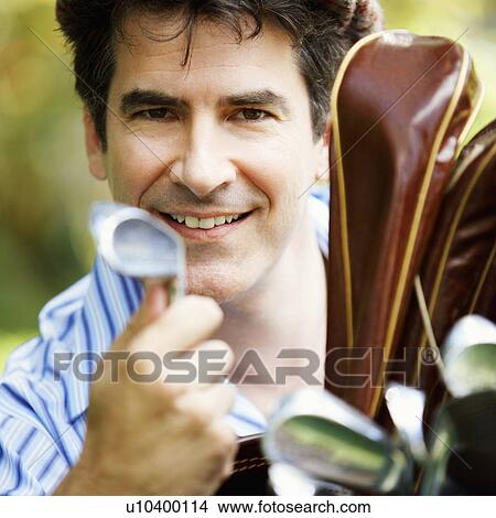 Picture - Portrait of a mature man holding a golf club and smiling. Fotosearch