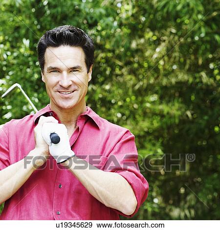 Stock Photo - Portrait of a mature man holding a golf club. Fotosearch