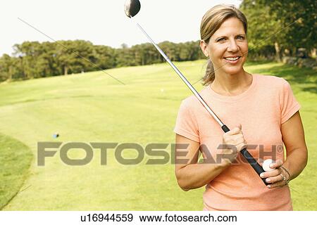 Portrait of a mature woman holding a golf club and a golf ball View Large Photo Image Stock Photo - Portrait of a mature woman holding a golf club and a golf ball. Fotosearch