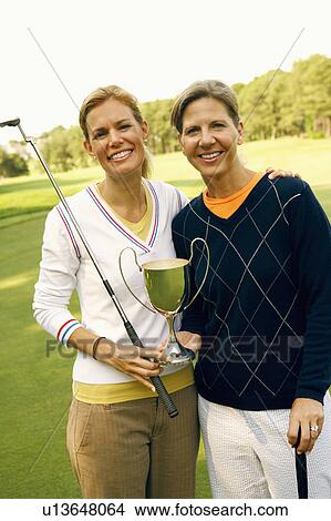 Portrait of a mid adult woman and a mature woman holding a trophy View Large Photo Image Picture - Portrait of a mid adult woman and a mature woman holding a trophy. Fotosearch