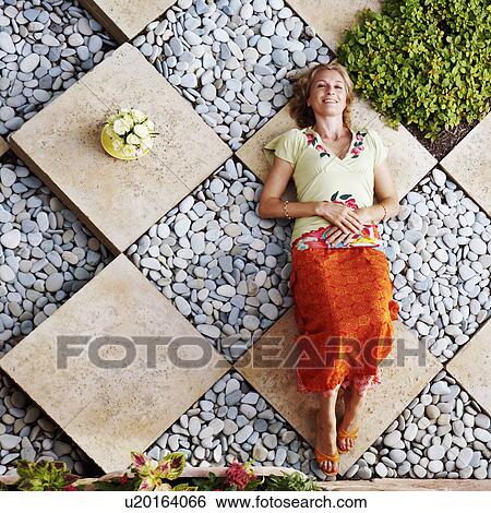 Stock Photograph - High angle view of a mature woman lying in a garden. Fotosearch