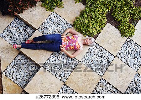 Stock Photograph - High angle view of a senior woman lying in a garden. Fotosearch