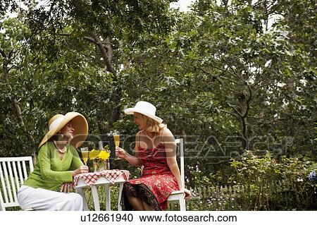 Mature woman and a senior woman sitting in a garden holding glasses of juice View Large Photo Image Stock Image - Mature woman and a senior woman sitting in a garden holding glasses of juice. Fotosearch